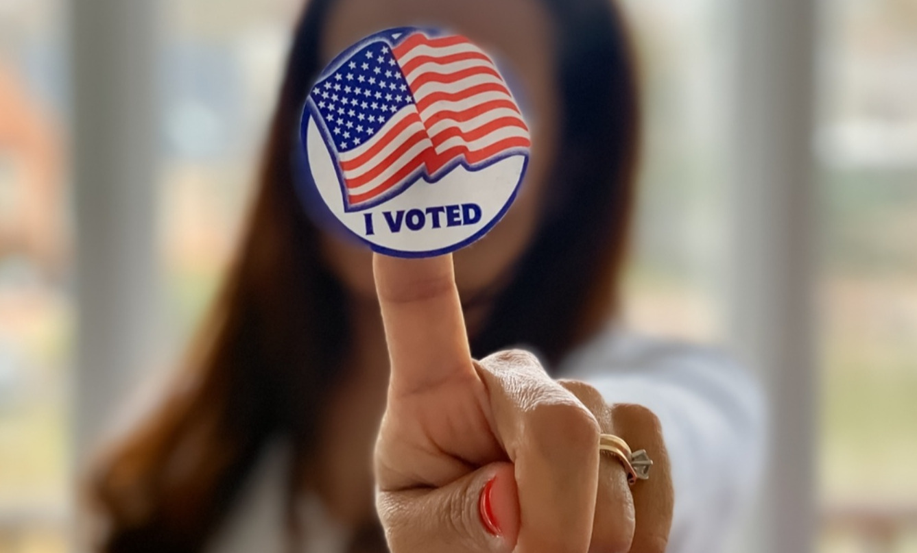 A woman holds out her hand with a sticker on her finger that says "I voted."